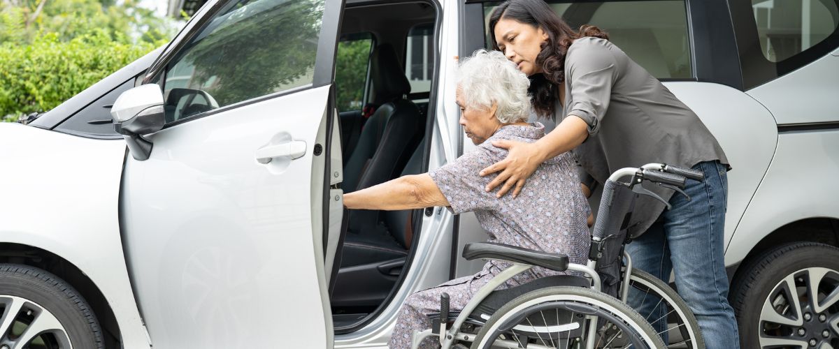 Elderly woman sitting on wheelchair entering the car