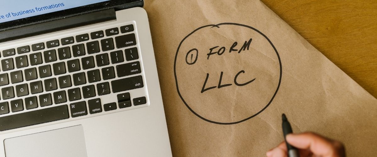 Form LLC written on paper beside laptop