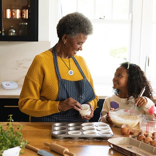 Grandma baking with granddaughter while wearing MGHome pendant