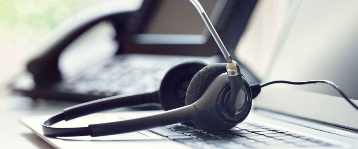 Headset headphones on laptop next to telephone