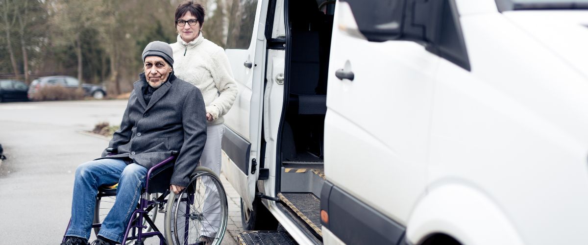 Nurse helping elderly man exiting a van